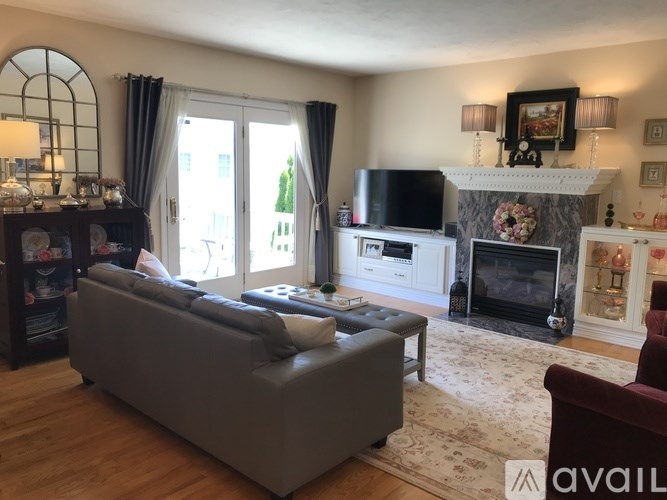 A living room with a grey couch, a fireplace, and a television.