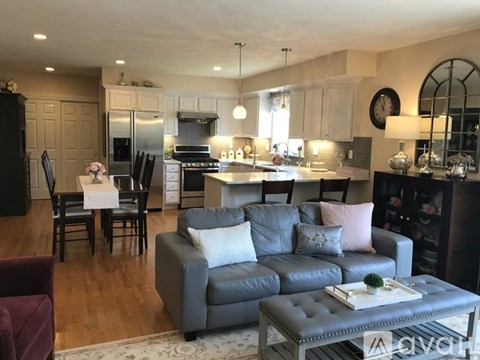 A modern living room with a grey sofa and a kitchen in the background.