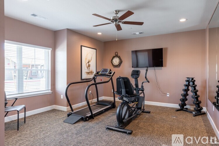 A well-equipped home gym with a treadmill, elliptical trainer, and dumbbells.