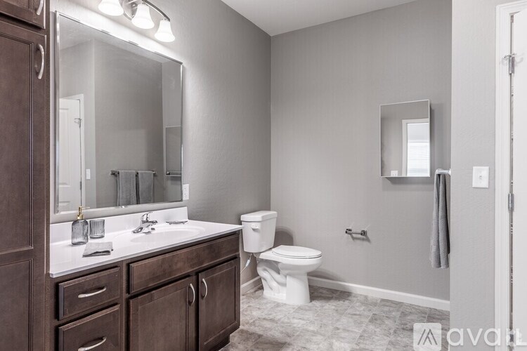 A bathroom with a toilet, sink, and mirror.
