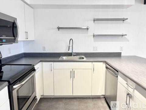 A kitchen with white cabinets and a black countertop.