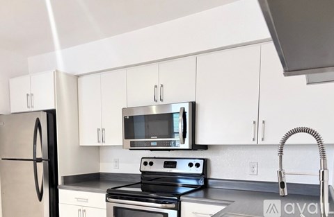 A kitchen with white cabinets and black appliances.