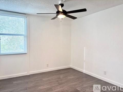A room with a ceiling fan and a window with blinds.