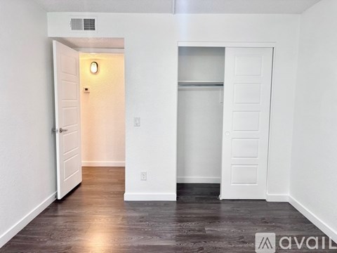 A room with a white door and a white closet with a light on.