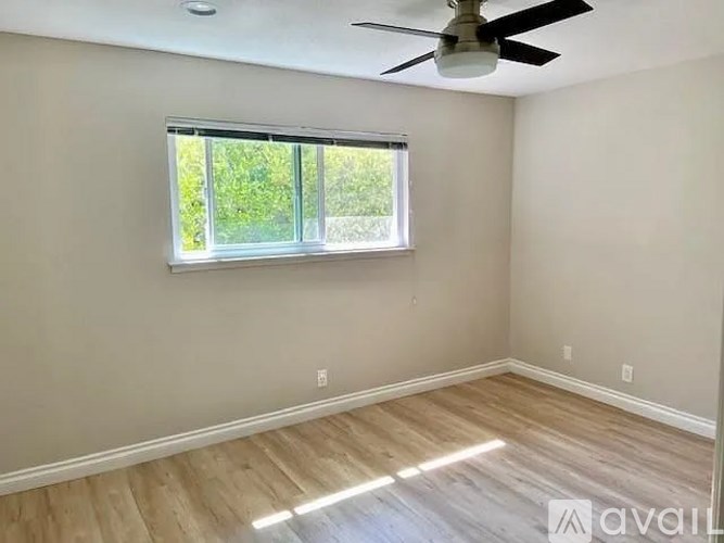 A room with a ceiling fan and a window with blinds.