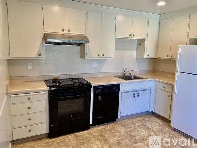 A kitchen with black appliances and white cabinets.