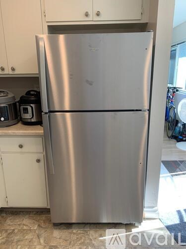 A silver refrigerator in a kitchen with white cabinets.