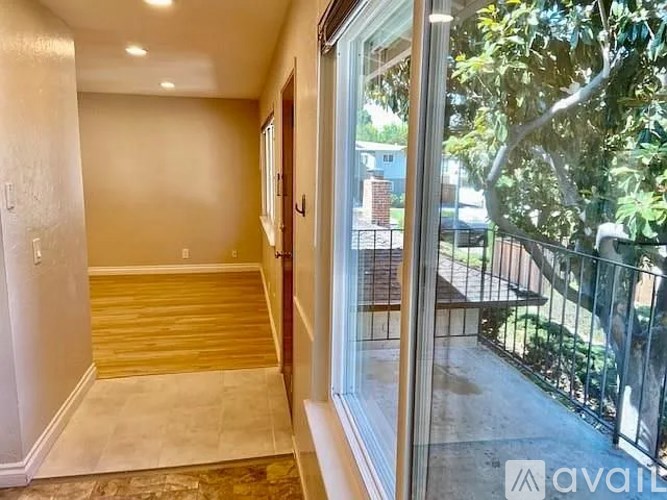 A room with a wooden floor and a glass door leading to a balcony.