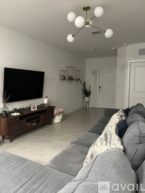 A living room with a grey couch and a wooden entertainment center.