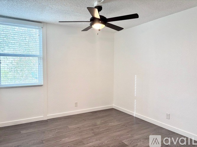 A room with a ceiling fan and a window with blinds.