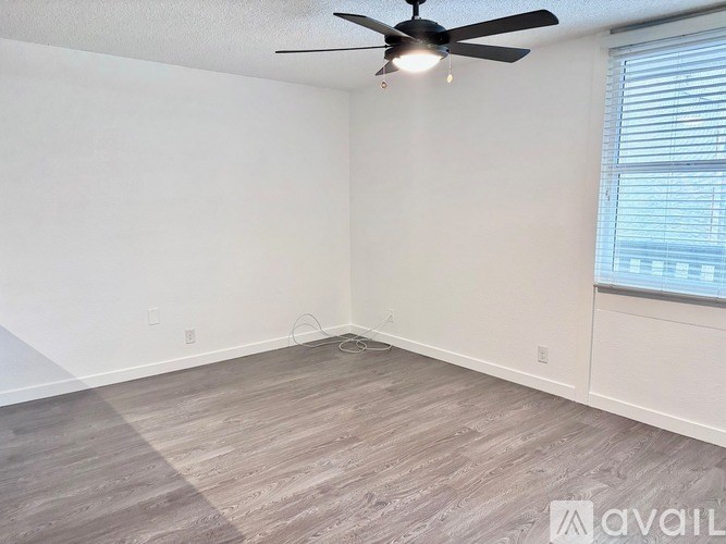A room with a ceiling fan and a window with blinds.