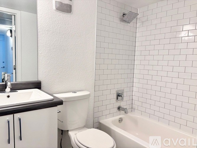 A white toilet sits next to a white bathtub in a bathroom with white tiles.