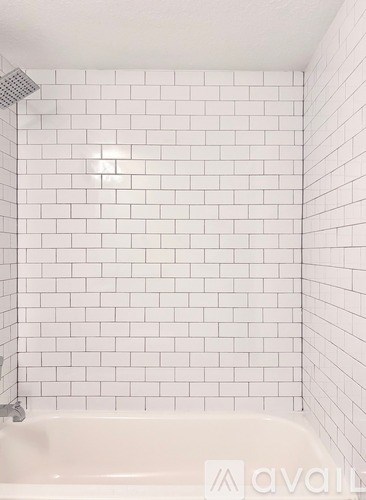 A white tiled shower with a white bathtub.