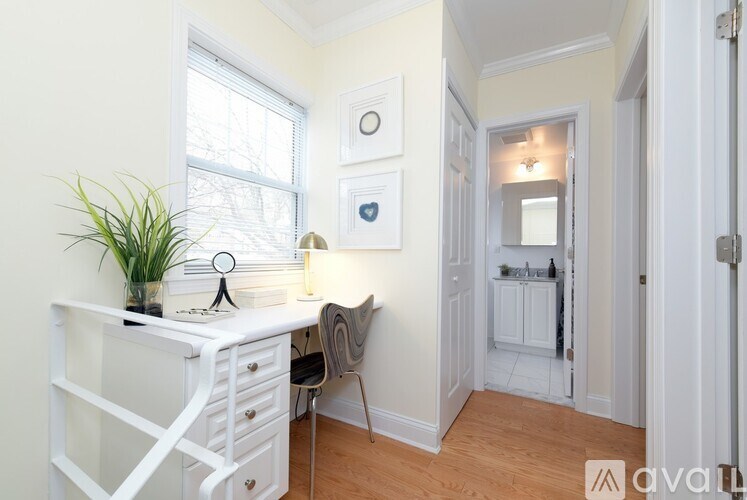 A white desk with a plant on it and a chair in front of it.