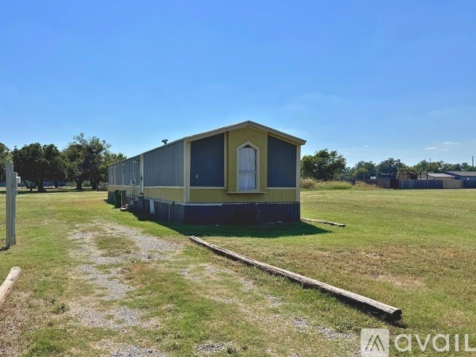 A small building with a yellow and blue exterior is situated in a grassy field.