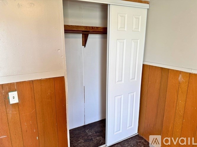 A white door is open to a room with wooden walls.