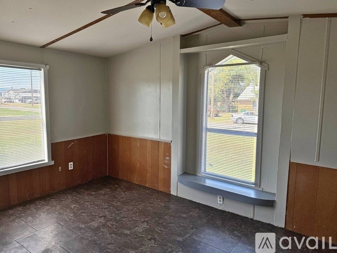 A room with a ceiling fan and two windows.