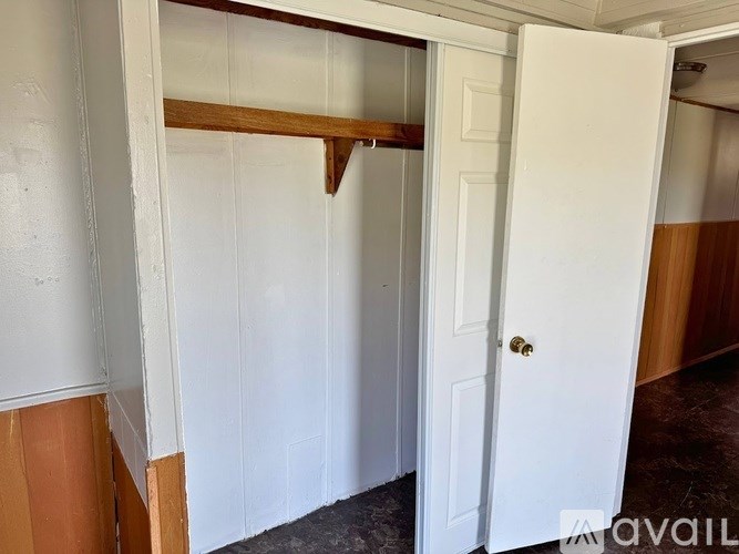 A white door is open to a room with a wooden shelf.