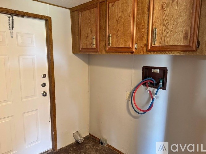 A white door is on the left of a wall with a box and wires on it.