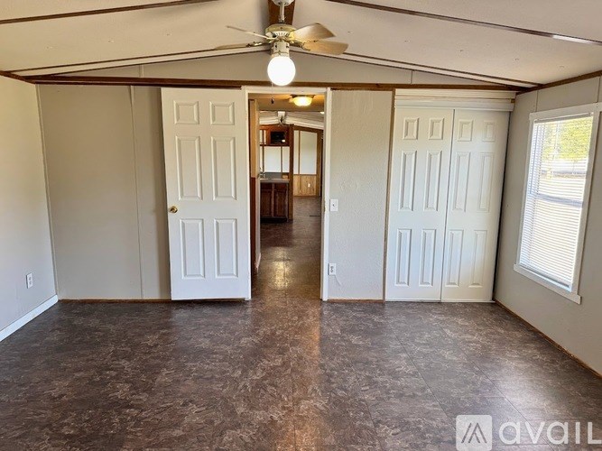 A room with a ceiling fan and a door leading to another room.