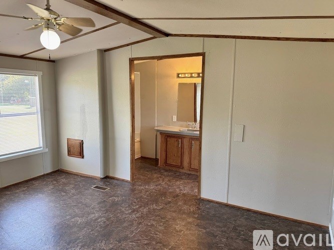 A room with a ceiling fan and a door leading to another room.