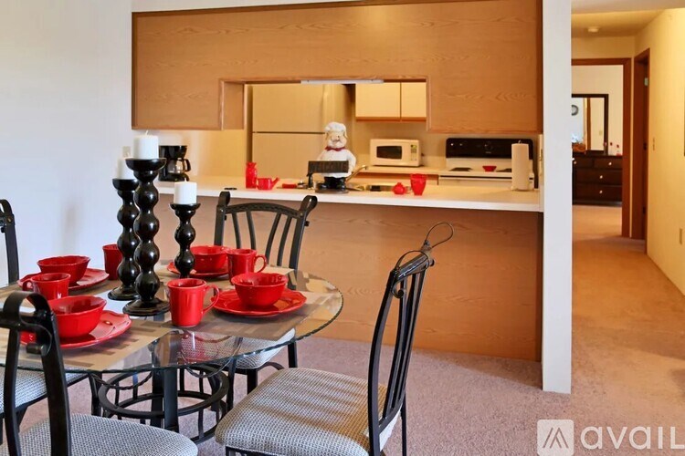 A modern kitchen with a glass table set for two.