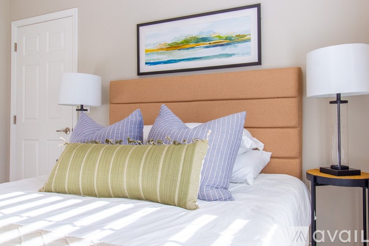 A bed with a striped pillow and a painting on the wall.