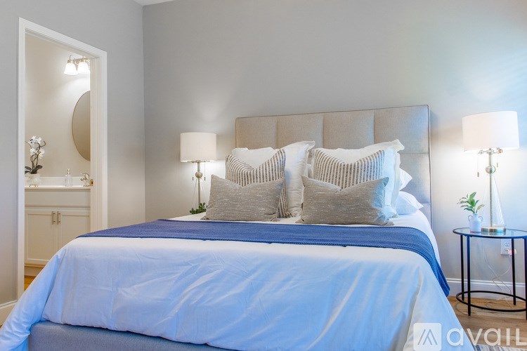 A bedroom with a large bed and a nightstand with a lamp.