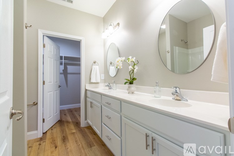 A bathroom with a white sink and a round mirror.