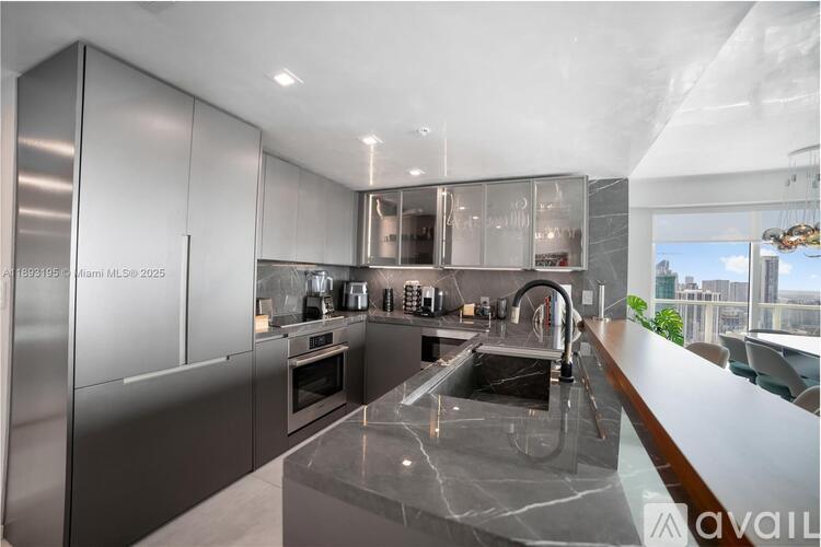 A modern kitchen with stainless steel appliances and a marble countertop.