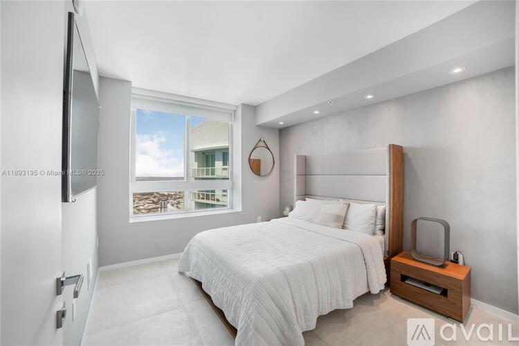 A bedroom with a large bed and a television on the wall.