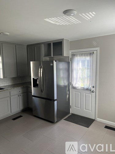 A kitchen with a refrigerator, cabinets, and a door.