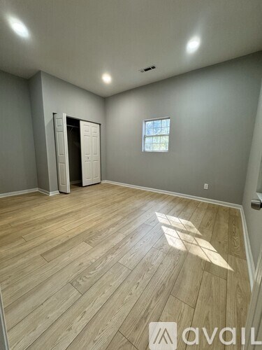 A room with wooden flooring and a window with sunlight coming through.