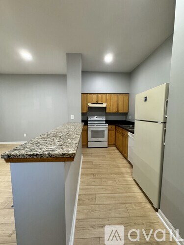 A kitchen with a granite countertop and a white refrigerator.