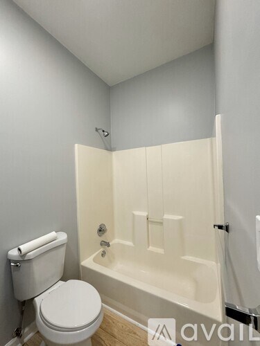 A white toilet sits next to a white bathtub in a small bathroom.