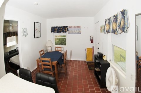 A living room with a sofa, a table, a chair and a fire extinguisher on the wall.