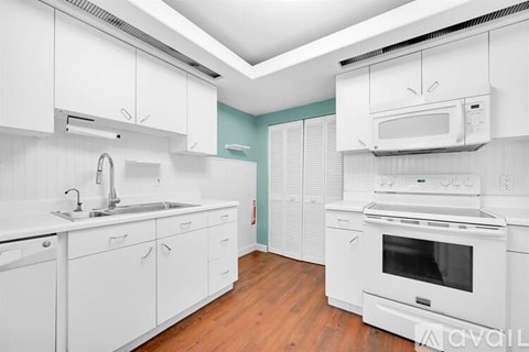 A modern kitchen with white cabinets and appliances.