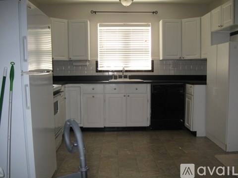 A kitchen with white cabinets and a black countertop.