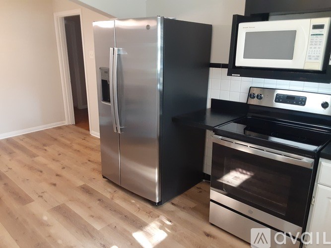 A kitchen with a stainless steel refrigerator, black countertops, and a microwave above the stove.