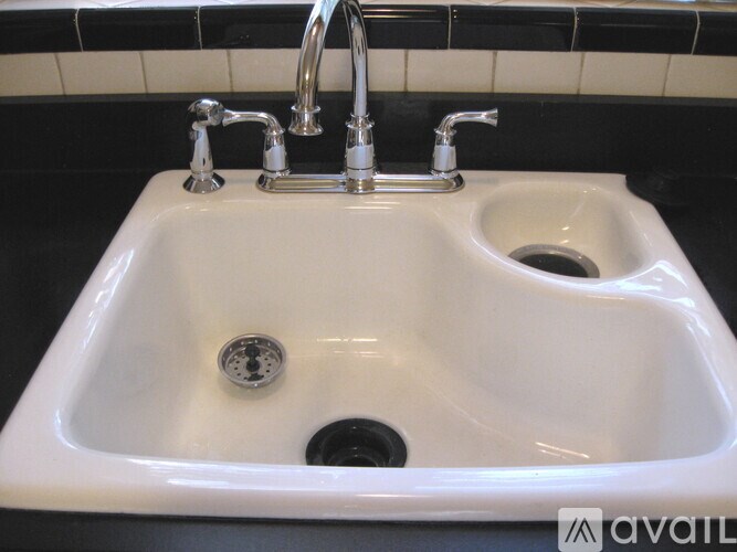 A white sink with a silver faucet and a drain in the middle.