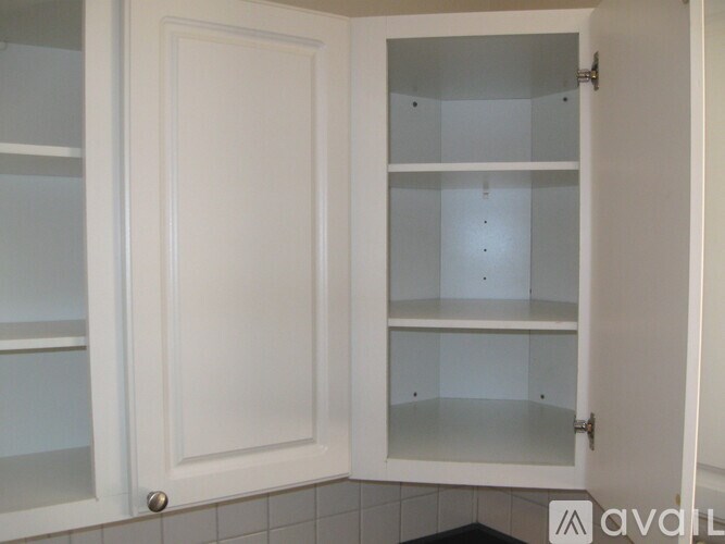 A white cabinet with glass shelves is open.