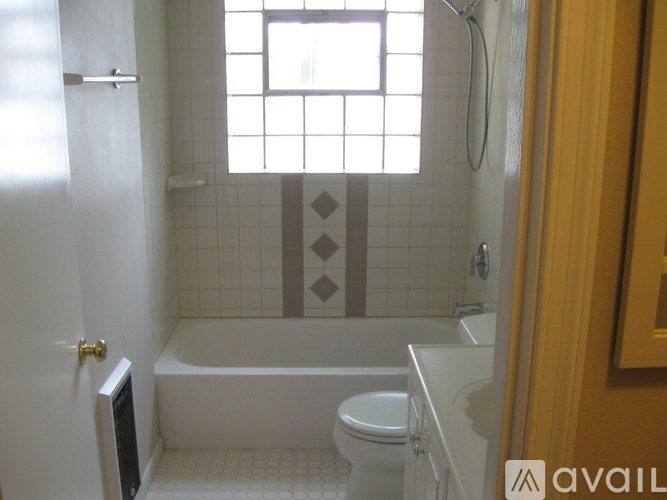 A bathroom with a bathtub, toilet, and a window.
