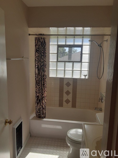 A bathroom with a toilet, tub, and window.