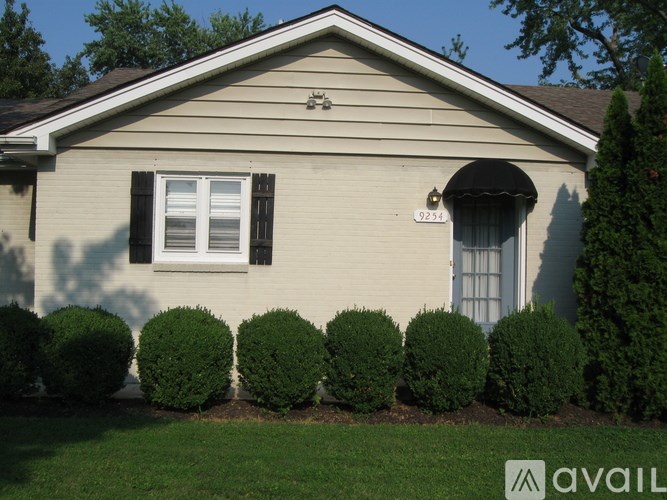 A house with a window and a black awning is numbered 923.