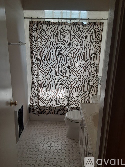 A bathroom with a zebra print shower curtain.