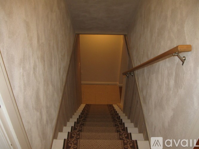 A staircase with a carpeted runner and wooden handrail.