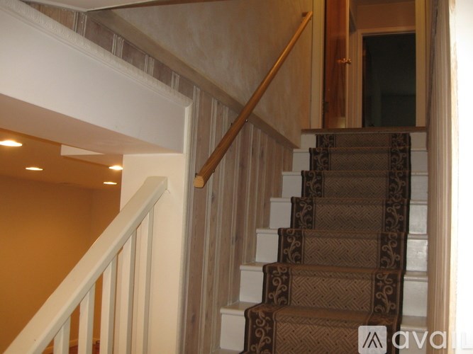 A staircase with a brown carpeted runner and white balusters.
