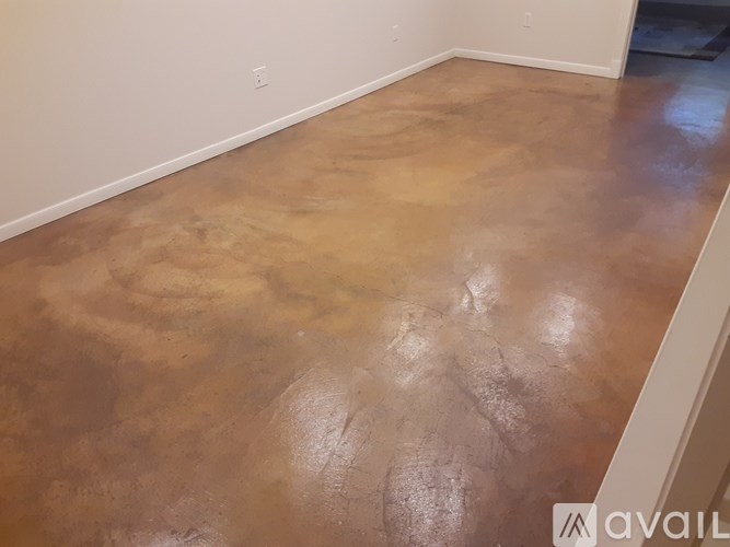 A room with a brown floor and white walls.