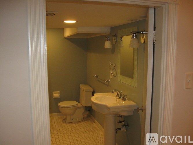 A bathroom with a toilet, sink, and mirror.