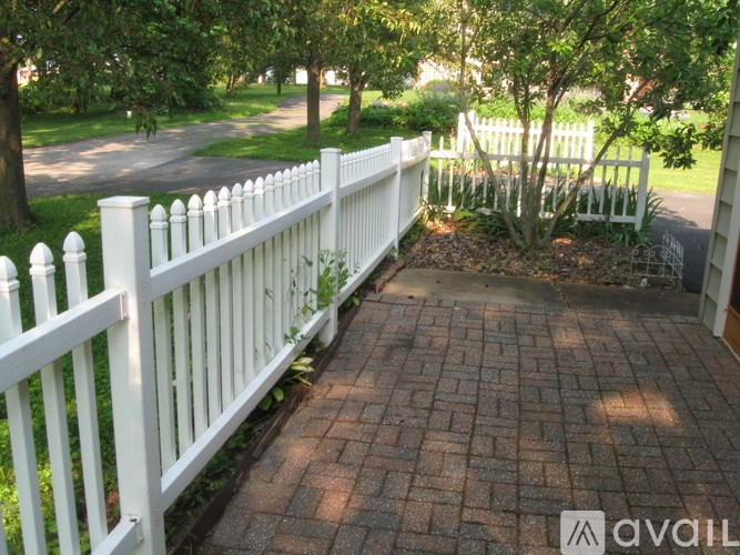 A white picket fence borders a brick walkway.